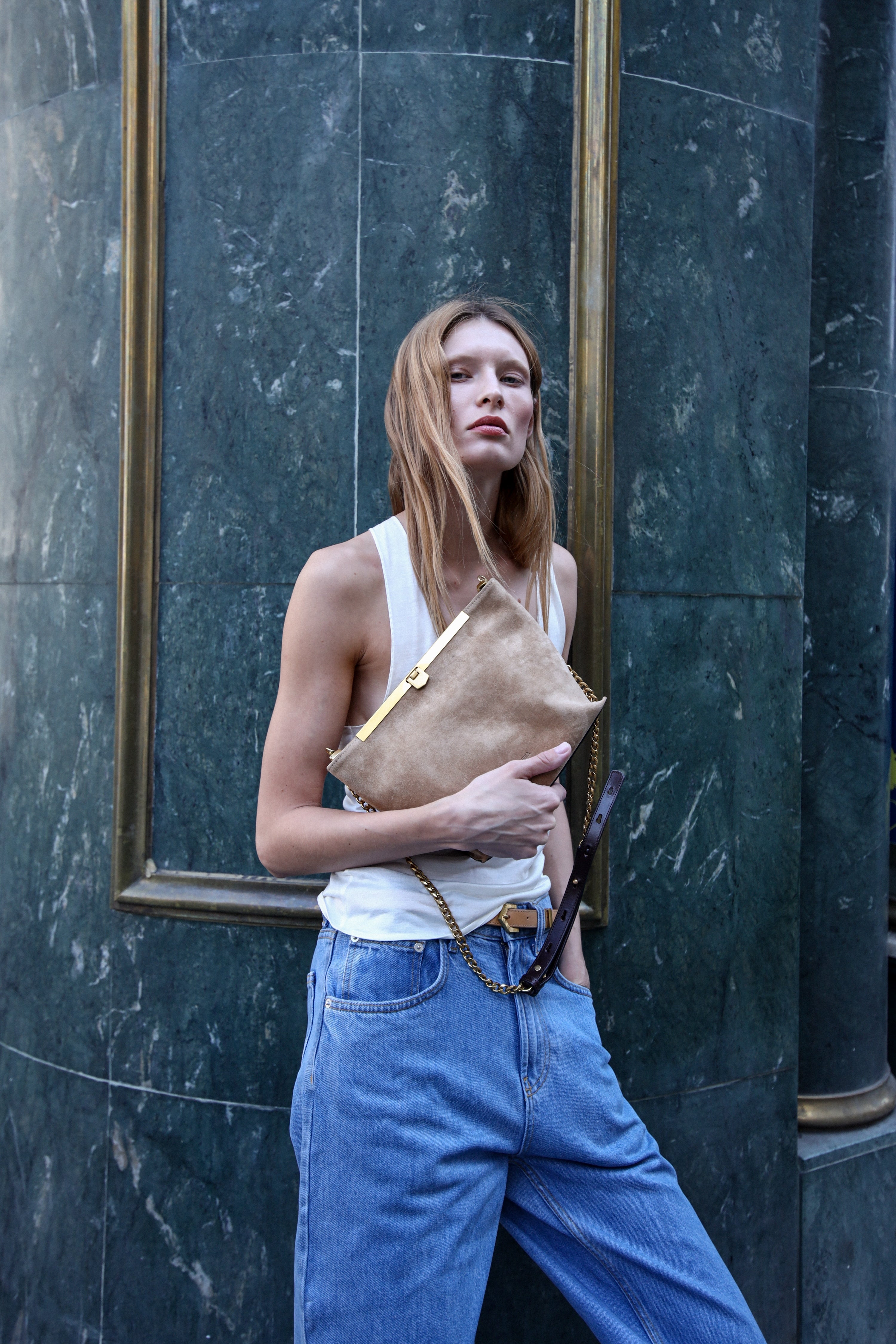 Estilismo del bolso de piel de ante modelo Petra color arena de la firma Mauska. Accesorio de alta marroquinería diseñado en San Sebastián y fabricado artesanalmente en los talleres de Ubrique, España. Se aprecia la textura premium de la piel de ante y el diseño contemporáneo de autor.