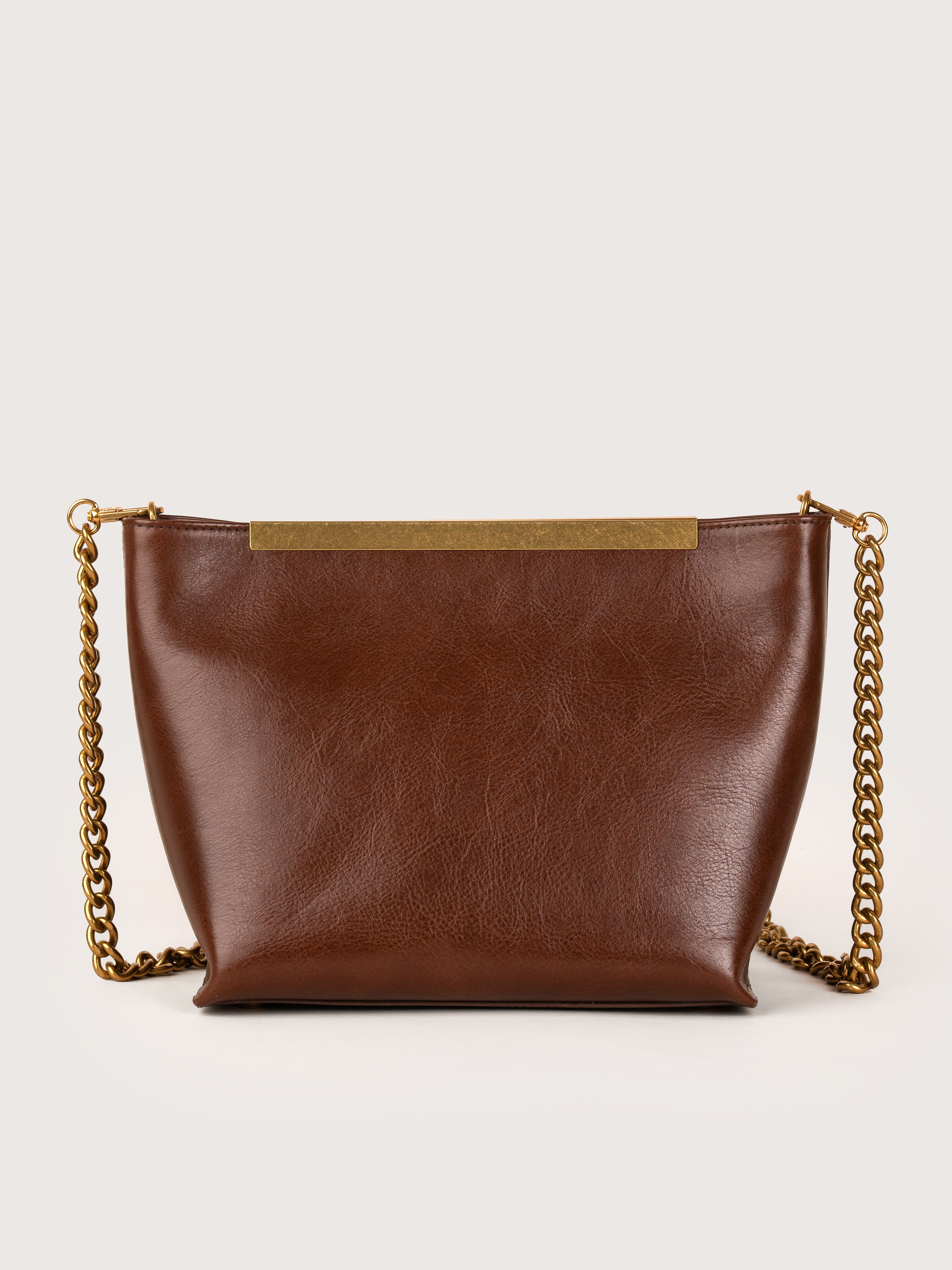 Vista trasera del bolso de piel modelo Petra color avellana de la firma Mauska. Accesorio de alta marroquinería diseñado en San Sebastián y fabricado artesanalmente en los talleres de Ubrique, España. Se aprecia la textura premium de la piel de ante y el diseño contemporáneo de autor.