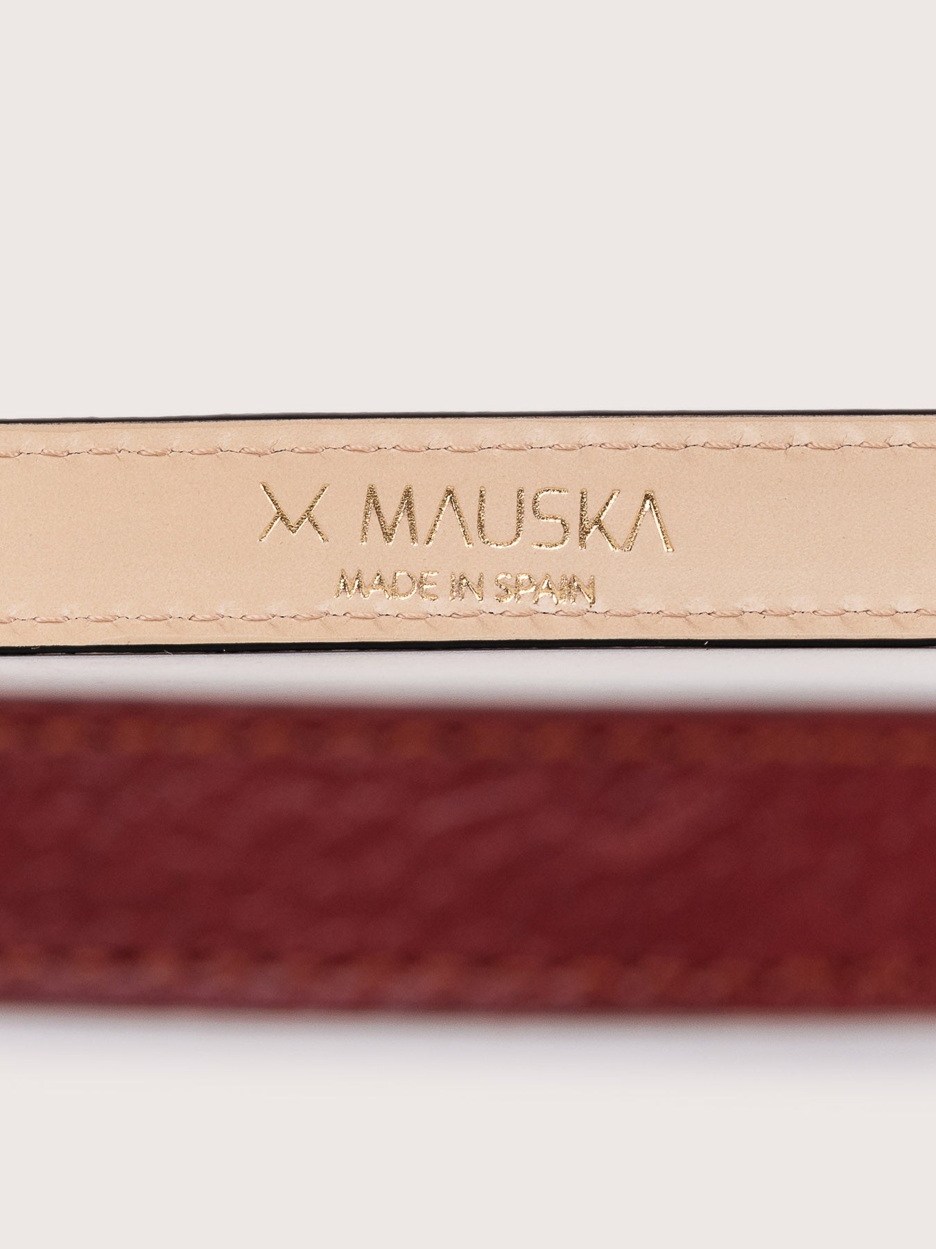 Vista detallada del cinturón de piel premium modelo Louna de la firma Mauska. Accesorio de alta marroquinería diseñado en San Sebastián y fabricado artesanalmente por maestros marroquineros en Ubrique, España. Se aprecia la calidad de la piel de vacuno, el acabado de los cantos pintados a mano y la hebilla de lujo