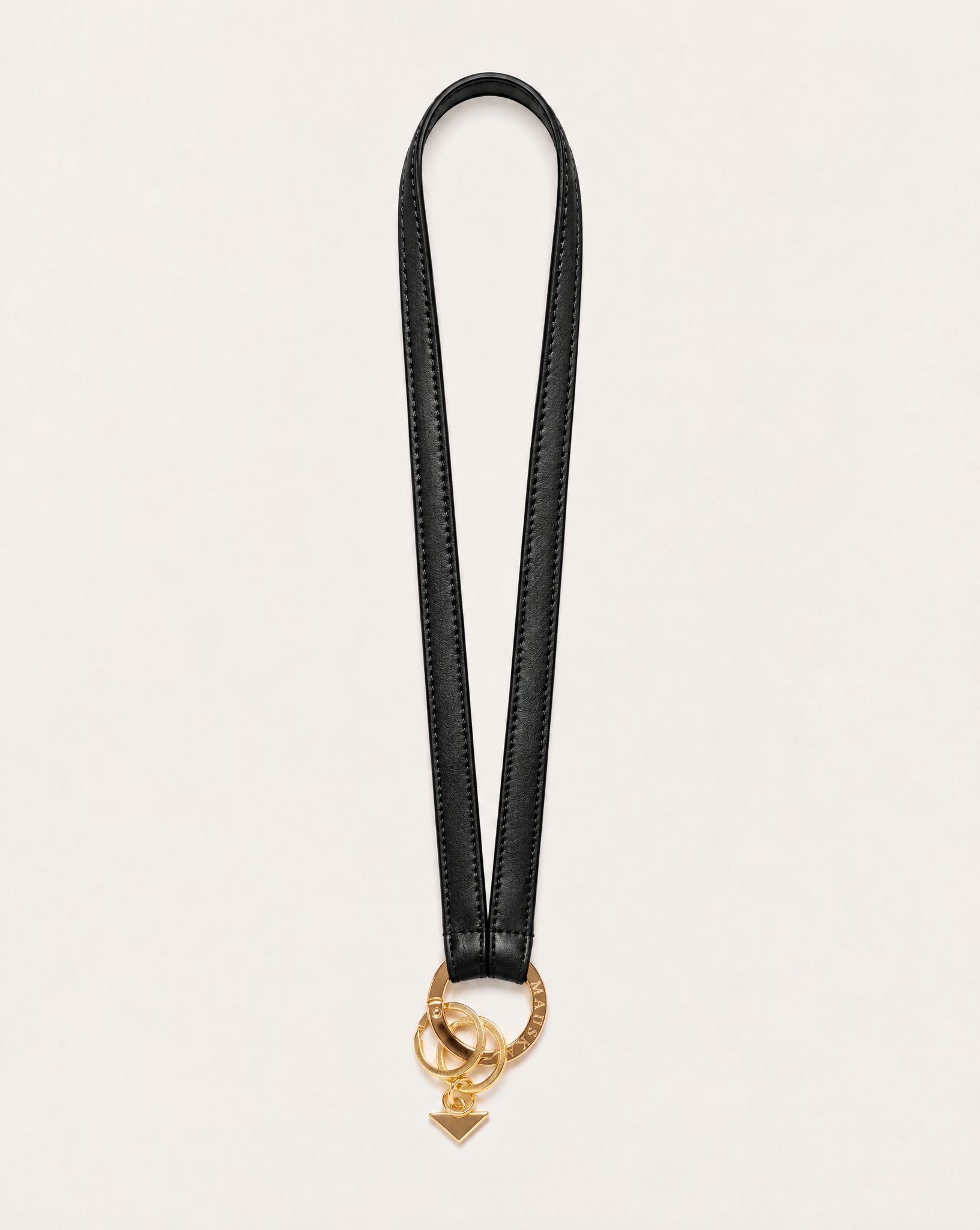 Texto alternativo: Full view of MAUSKA ARO blackvegetable-tanned leather neck key holder with gold-tone circular clasp and key rings.