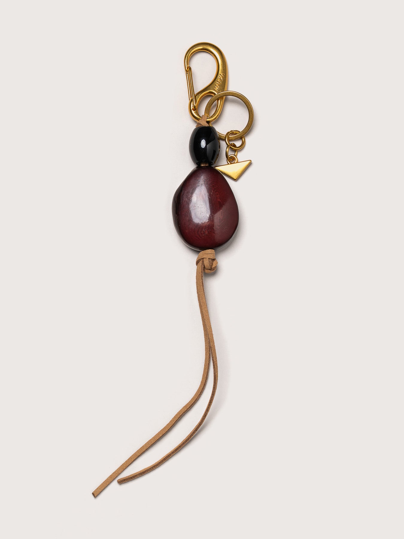 Detail of the Tagua leather key charm in burgundy by Mauska. Luxury micro-leather accessory designed in San Sebastián and handcrafted by master artisans in Ubrique, Spain. Showcasing premium leather quality and high-end hardware finish.