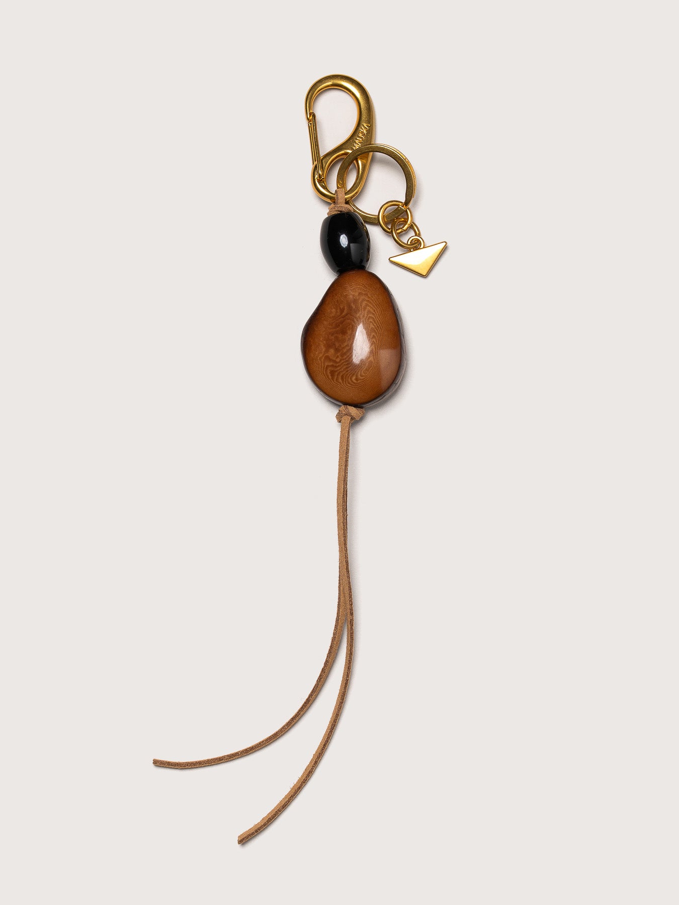 Detail of the Tagua leather key charm in hazelnut by Mauska. Luxury micro-leather accessory designed in San Sebastián and handcrafted by master artisans in Ubrique, Spain. Showcasing premium leather quality and high-end hardware finish.