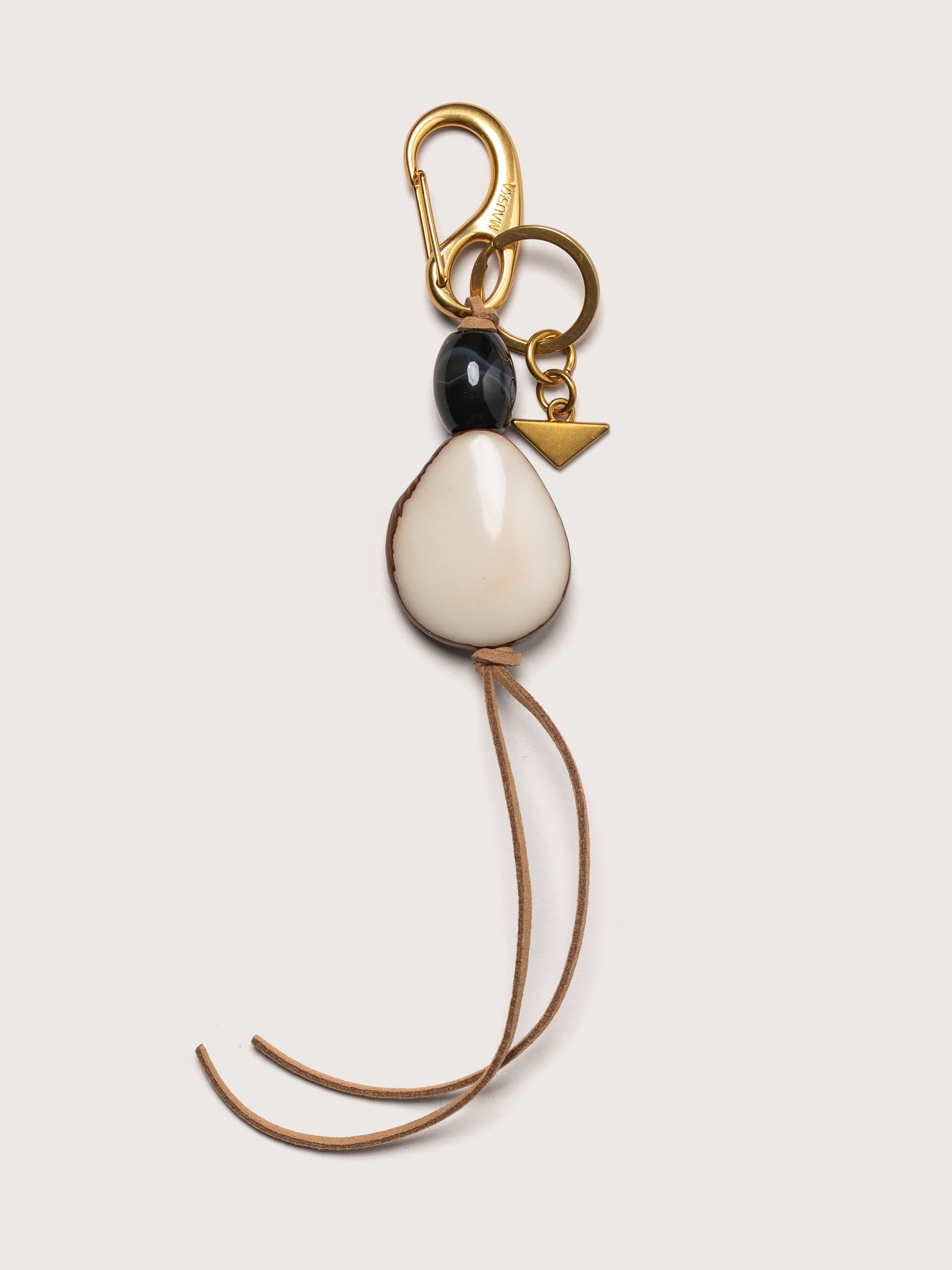 Detail of the Tagua leather key charm in ivory by Mauska. Luxury micro-leather accessory designed in San Sebastián and handcrafted by master artisans in Ubrique, Spain. Showcasing premium leather quality and high-end hardware finish.