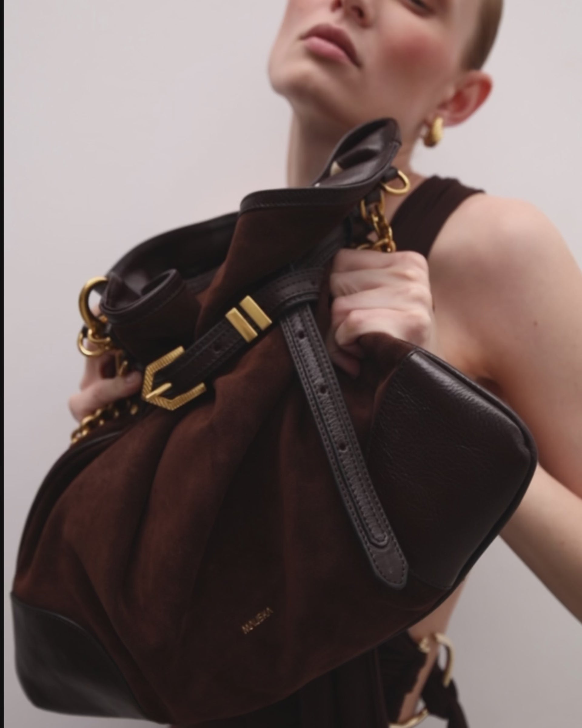 Vista  frontal del bolso de piel de ante modelo Pereira maxi color ébano de la firma Mauska. Accesorio de alta marroquinería diseñado en San Sebastián y fabricado artesanalmente en los talleres de Ubrique, España. Se aprecia la textura premium de la piel de ante y el diseño contemporáneo de autor.